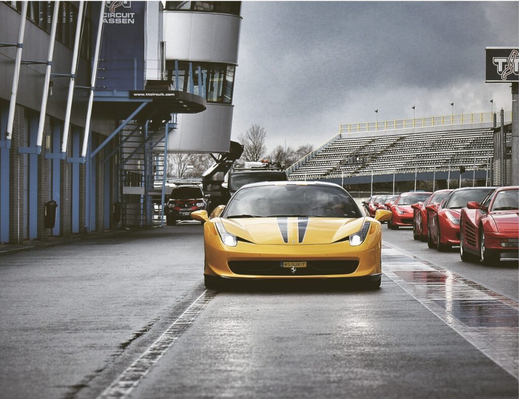 Yellow sports car with black vehicle graphics racing stripe kit on race track with other cars behind by Classic Pinstriping in Dallas Fort Worth Metroplex